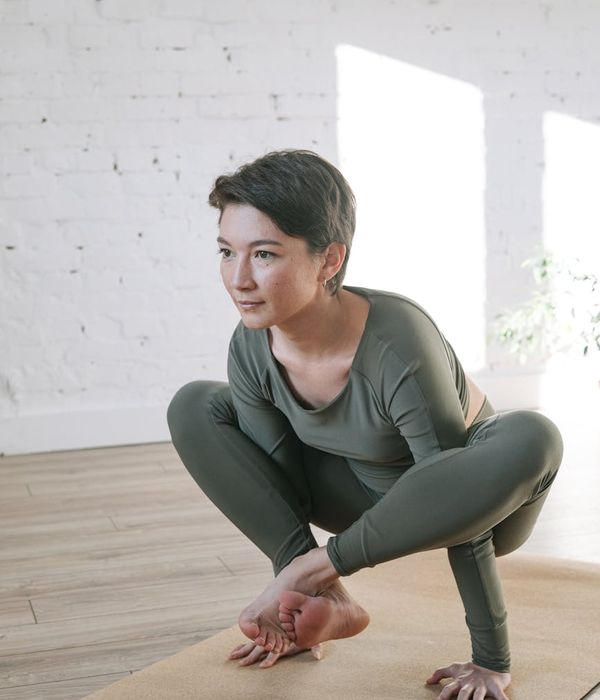 Woman in a relaxed yoga pose in a bright, peaceful room.